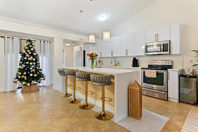 kitchen featuring sink, hanging light fixtures, white cabinets, a kitchen island, and appliances with stainless steel finishes