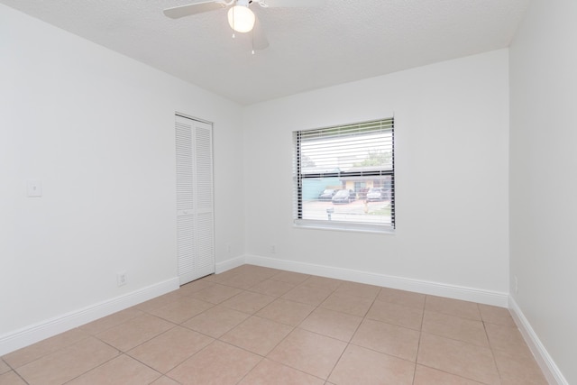 spare room with ceiling fan, light tile patterned floors, and a textured ceiling