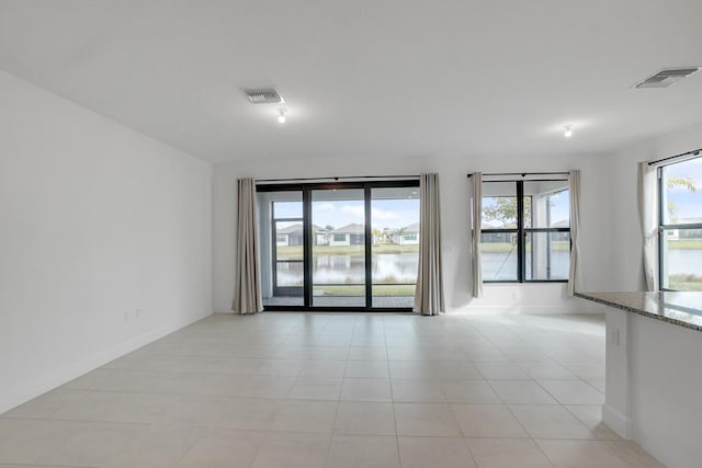 spare room featuring a water view and light tile patterned floors