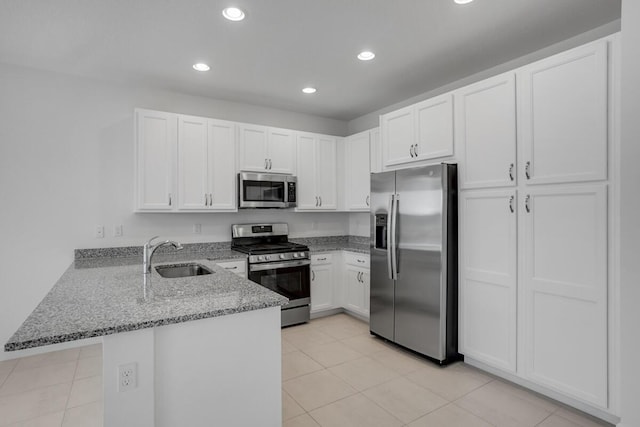 kitchen featuring sink, kitchen peninsula, light stone counters, white cabinetry, and stainless steel appliances