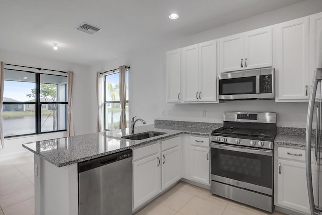 12535 SW Blue Mangrove Pkwy, Port Saint Lucie, FL 34987 - kitchen with appliances with stainless steel finishes, a sink, a peninsula, white cabinets, and light tile patterned floors