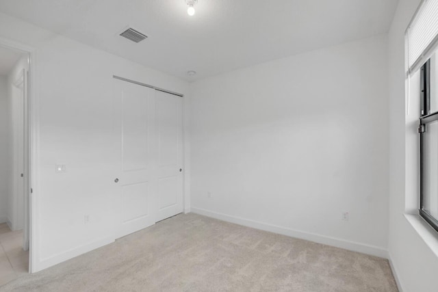 unfurnished bedroom featuring a closet and light colored carpet