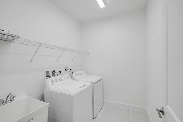 laundry room with light tile patterned flooring, washing machine and dryer, and sink