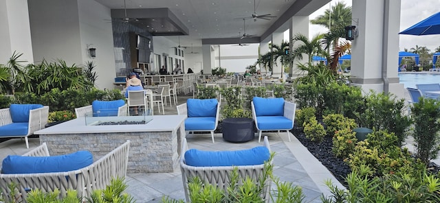 view of patio featuring a fire pit, ceiling fan, and exterior bar