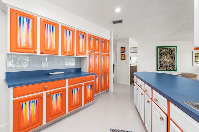 kitchen featuring white cabinets, a textured ceiling, and tasteful backsplash