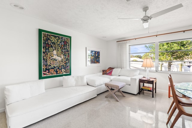 living room featuring ceiling fan and a textured ceiling