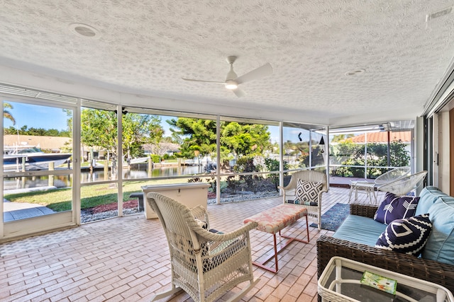 sunroom / solarium featuring ceiling fan and a water view