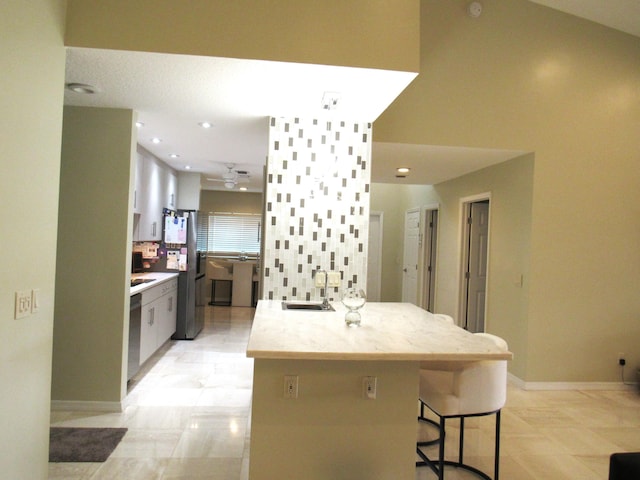 kitchen featuring sink, stainless steel appliances, tasteful backsplash, kitchen peninsula, and a breakfast bar area