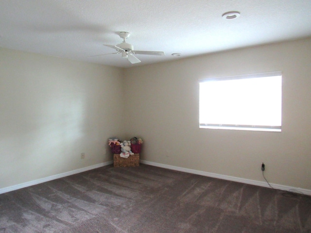 empty room with dark colored carpet and ceiling fan