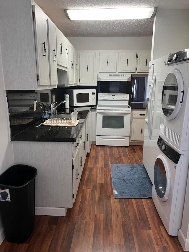 kitchen featuring a textured ceiling, dark wood-type flooring, stacked washing maching and dryer, and white appliances