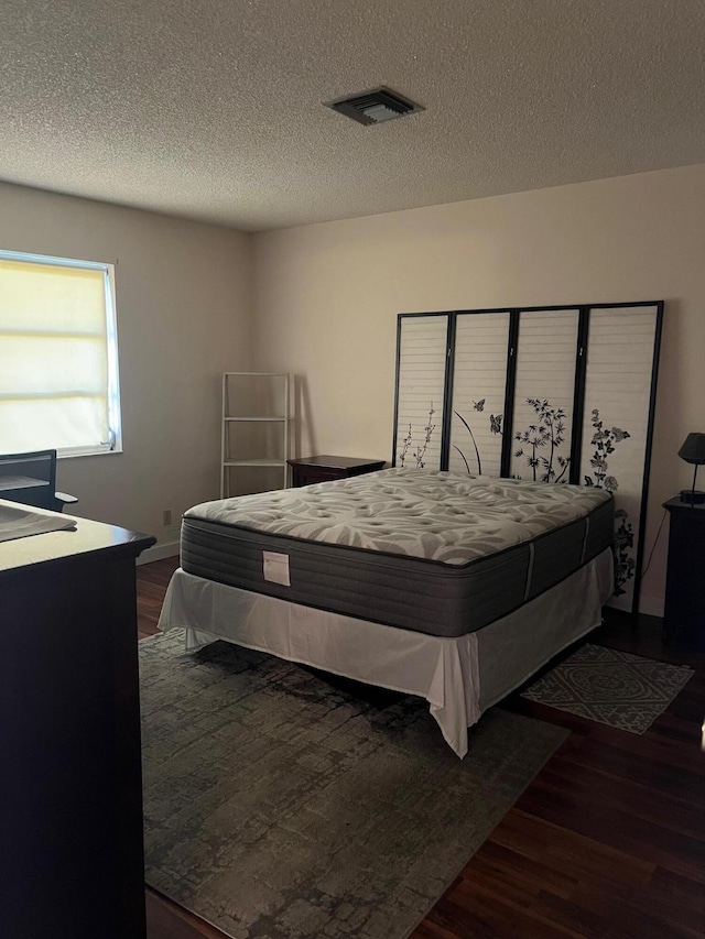 bedroom featuring a textured ceiling and dark wood-type flooring