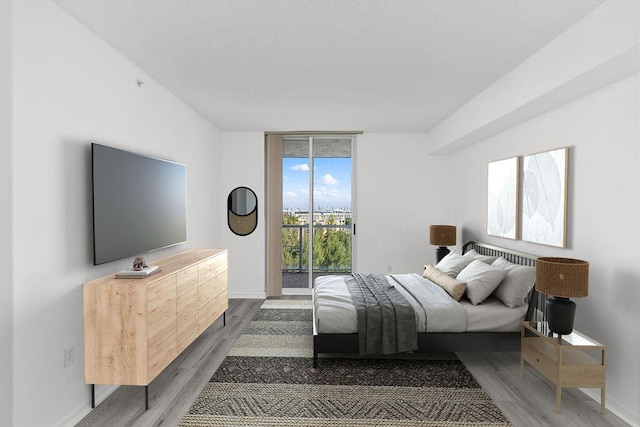 bedroom featuring access to exterior, expansive windows, and wood-type flooring