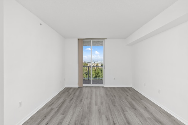 spare room featuring light hardwood / wood-style flooring and floor to ceiling windows