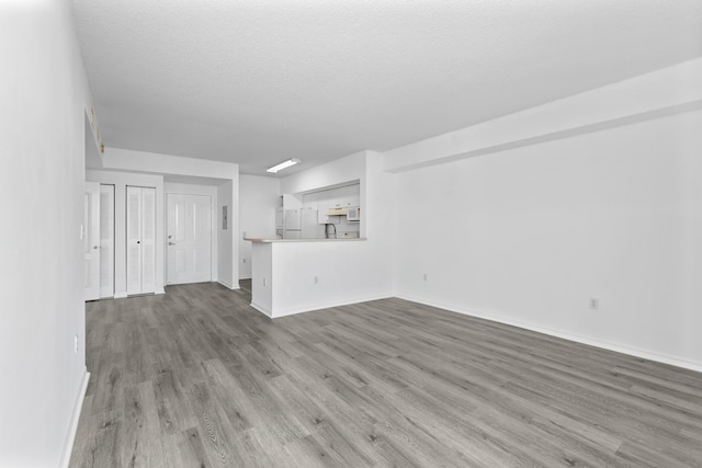 unfurnished living room with wood-type flooring and a textured ceiling