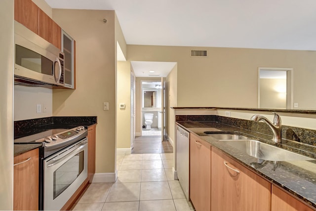 700 E Boynton Beach Blvd Unit 407, Boynton Beach, FL 33435 - kitchen featuring appliances with stainless steel finishes, a sink, dark stone counters, light tile patterned floors, and glass insert cabinets