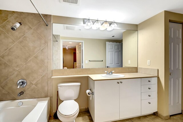 full bathroom featuring tile patterned flooring, vanity, tiled shower / bath combo, and toilet