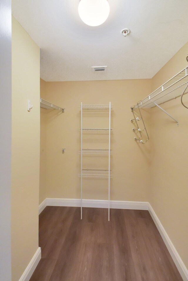 laundry room featuring stacked washing maching and dryer and light hardwood / wood-style floors