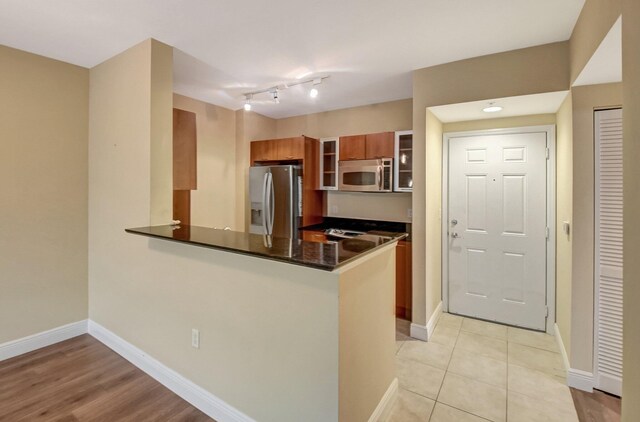 kitchen with light tile patterned flooring, appliances with stainless steel finishes, dark stone counters, and sink