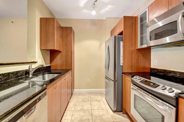 kitchen with appliances with stainless steel finishes, light tile patterned floors, and dark stone countertops