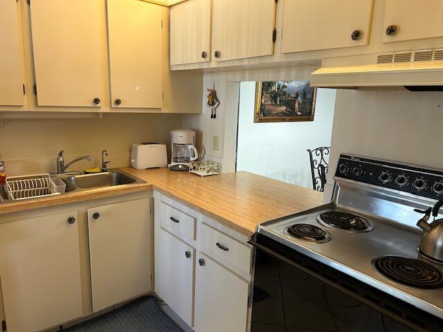 kitchen featuring range with electric stovetop, white cabinetry, sink, and exhaust hood