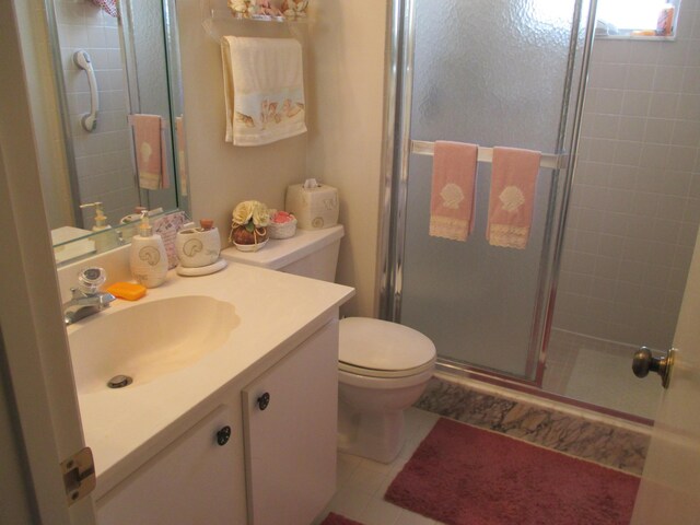 bathroom with tile patterned floors, vanity, a shower with shower door, and toilet