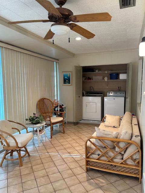 living room with ceiling fan, washing machine and dryer, and light tile patterned floors