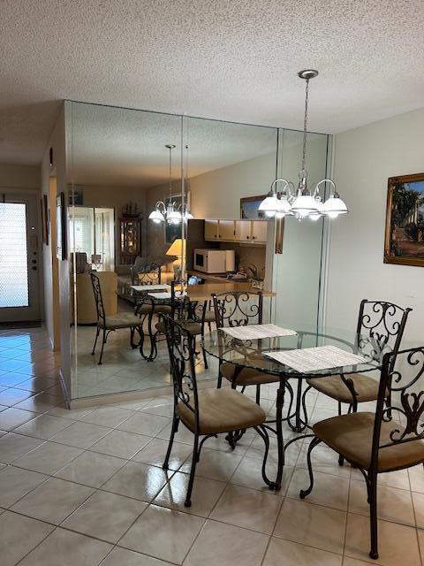 tiled dining area featuring a textured ceiling and an inviting chandelier