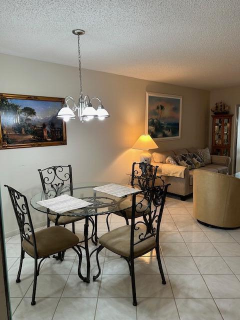 tiled dining area featuring a textured ceiling and an inviting chandelier