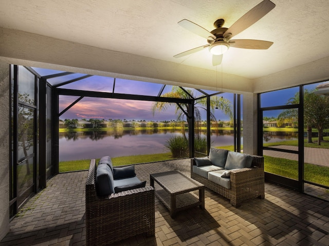 sunroom / solarium featuring ceiling fan and a water view