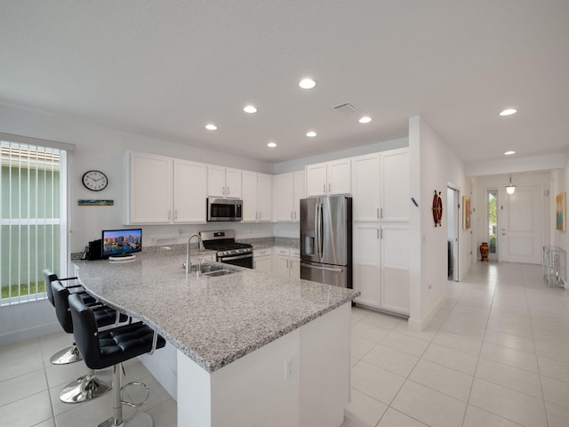 kitchen featuring kitchen peninsula, white cabinetry, light stone counters, and appliances with stainless steel finishes