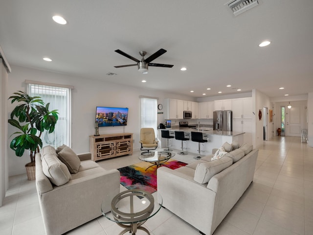 living room with ceiling fan, sink, and light tile patterned floors