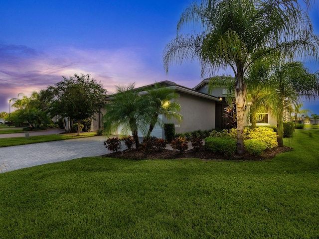 property exterior at dusk featuring a lawn