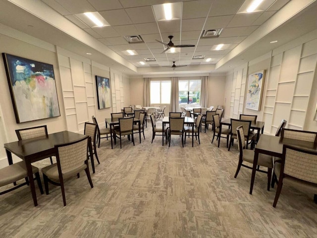 carpeted dining area featuring ceiling fan and a drop ceiling