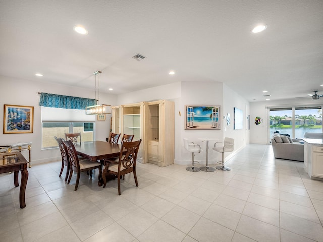 tiled dining room featuring a water view and ceiling fan