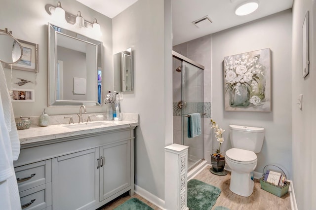 bathroom featuring hardwood / wood-style flooring, vanity, a shower with shower door, and toilet