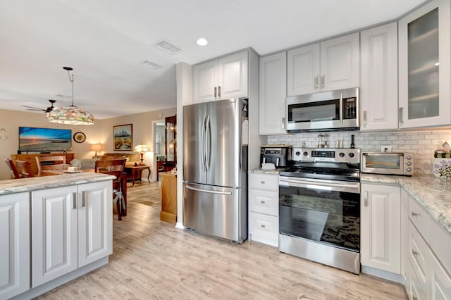 kitchen with tasteful backsplash, light stone counters, stainless steel appliances, ceiling fan, and hanging light fixtures