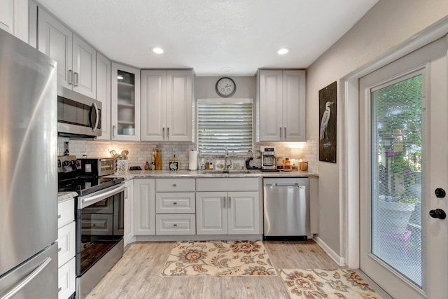 kitchen featuring light stone countertops, sink, light wood-type flooring, and stainless steel appliances