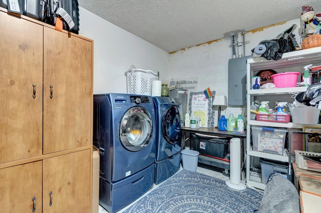 laundry room with a textured ceiling, washing machine and dryer, and electric panel