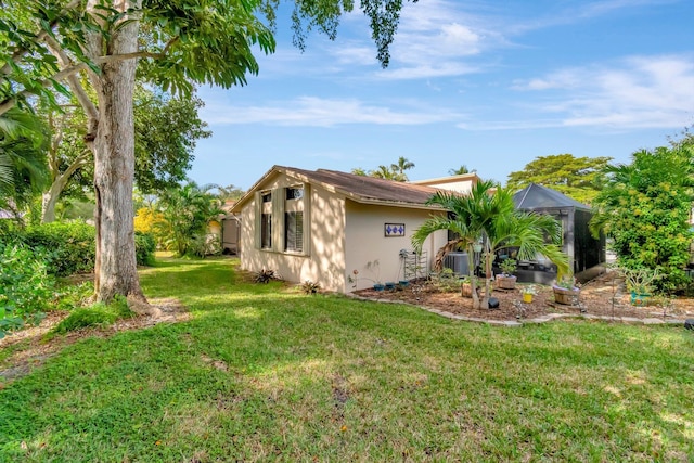 view of side of home with cooling unit, a lanai, and a lawn