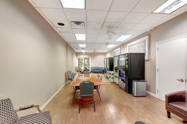 dining space with light wood-type flooring, a paneled ceiling, and ceiling fan