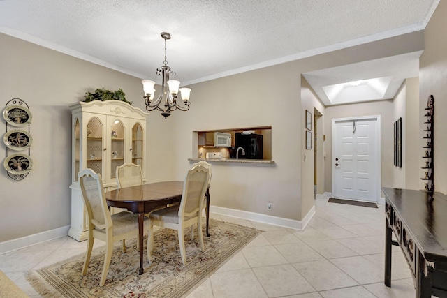 tiled dining space featuring sink, a chandelier, a textured ceiling, vaulted ceiling with skylight, and ornamental molding