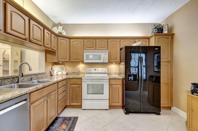 kitchen featuring a textured ceiling, sink, light tile patterned floors, and white appliances