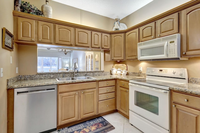 kitchen featuring light stone countertops, white appliances, sink, light tile patterned floors, and a notable chandelier