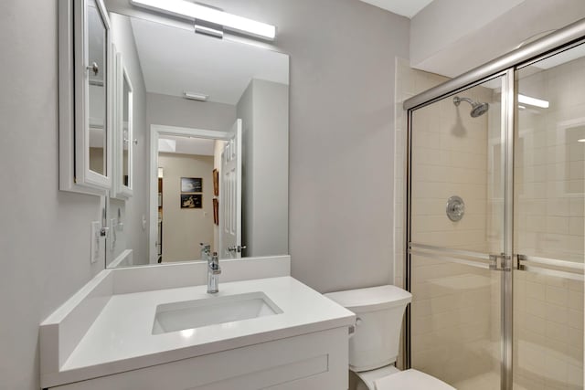 bathroom with walk in shower, vanity, and toilet