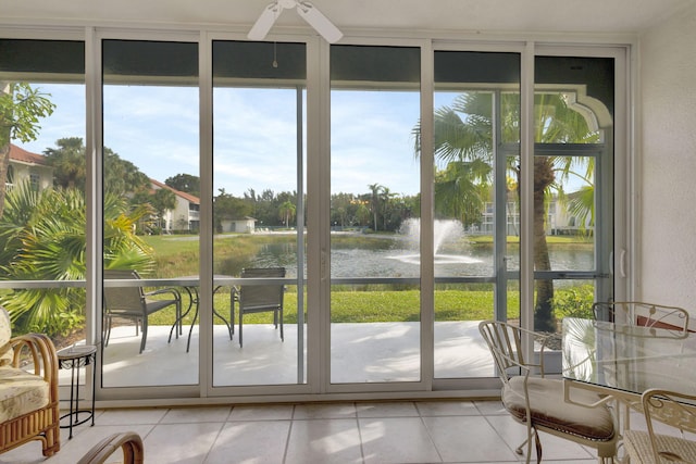 entryway featuring ceiling fan, a water view, light tile patterned floors, and a wall of windows