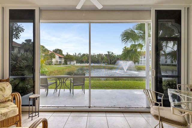 sunroom with ceiling fan and a water view