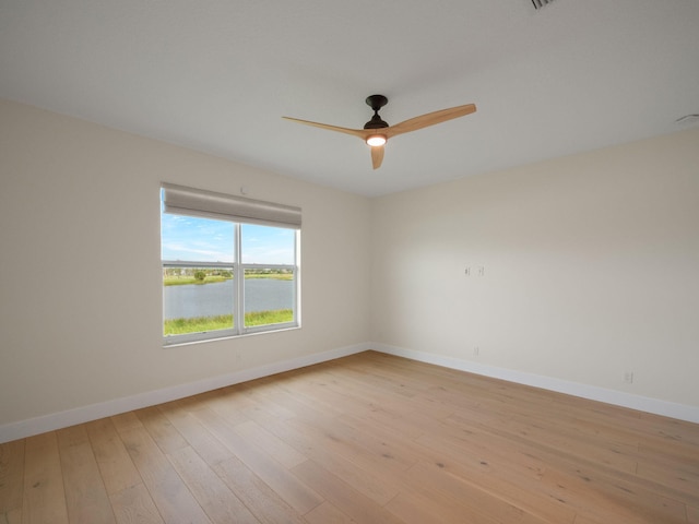 unfurnished room featuring ceiling fan, a water view, and light hardwood / wood-style flooring