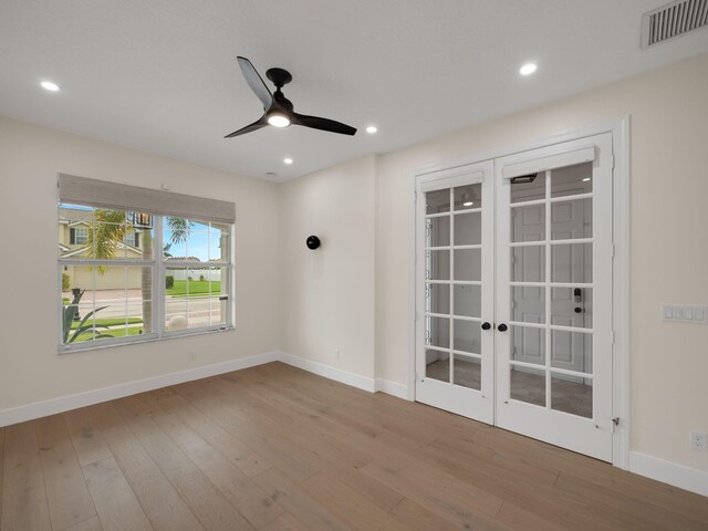 empty room with hardwood / wood-style flooring, ceiling fan, and french doors