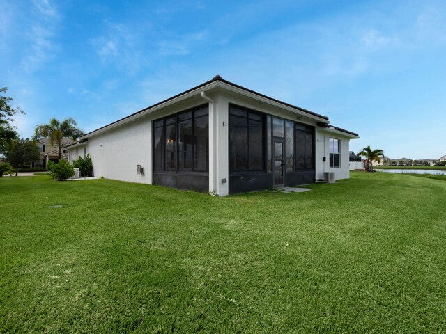 view of side of home with a sunroom and a yard