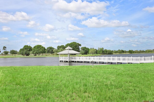 dock area with a lawn, a water view, and a gazebo